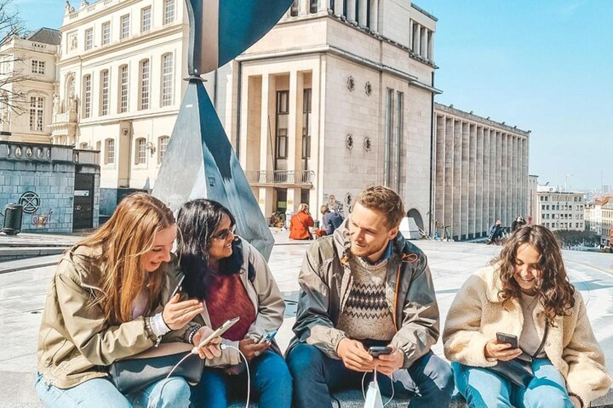 skupina ljudi, ki sedijo na tleh in gledajo v svoje mobilne telefone