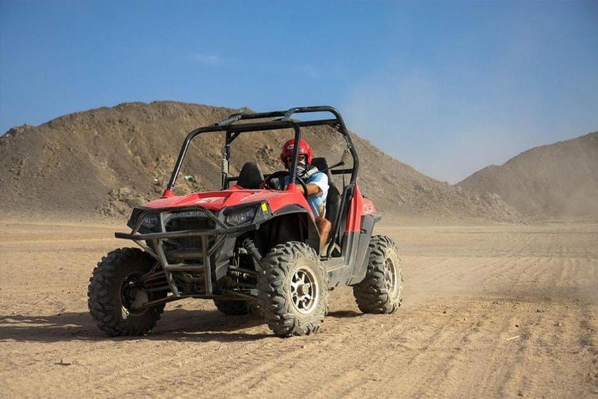 a man driving a red atv in the desert