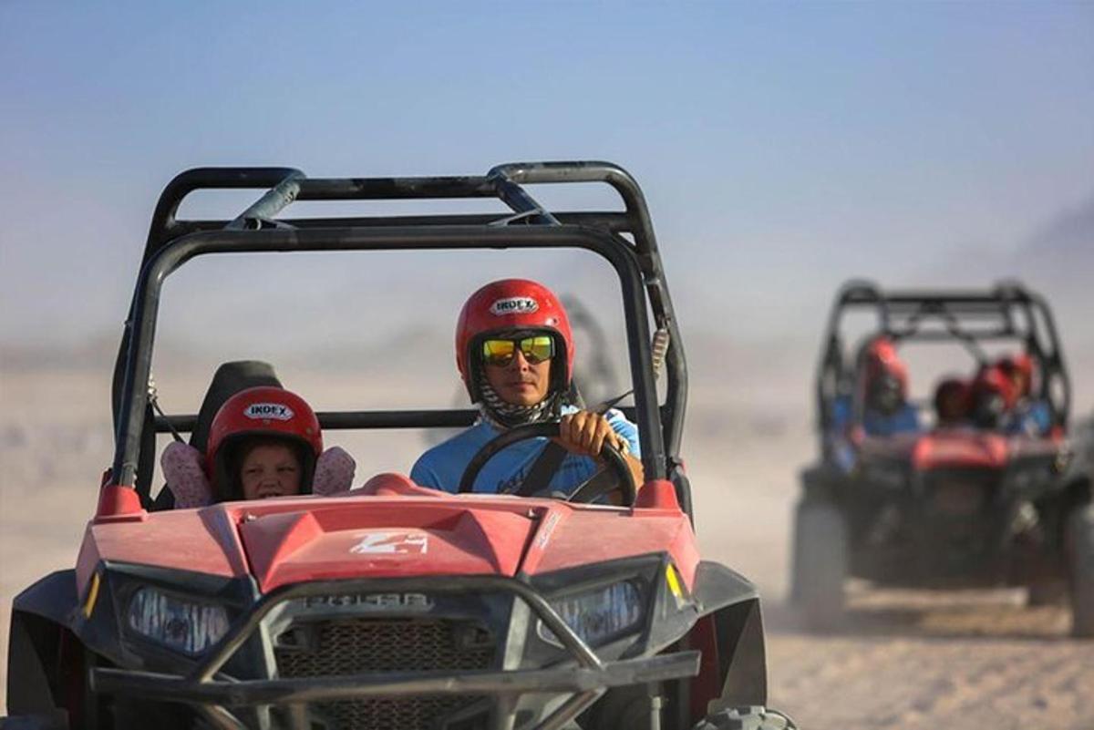 duas pessoas andando em um quadriciclo no deserto
