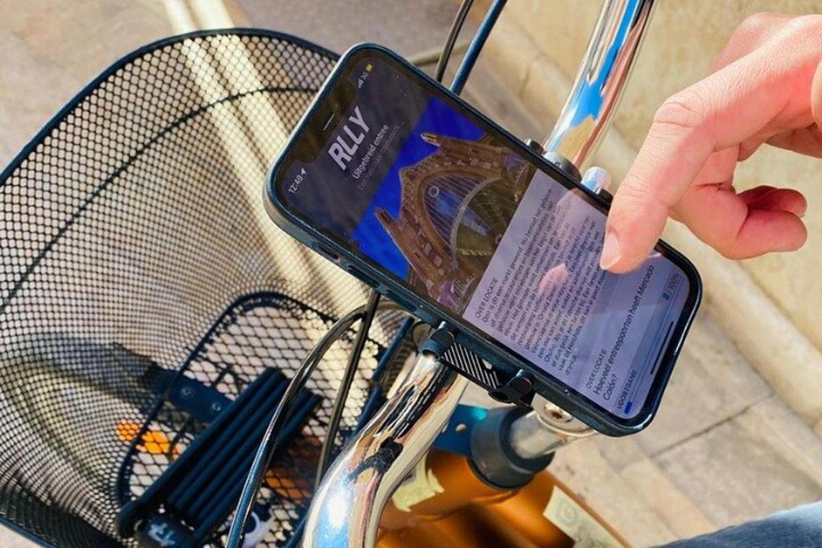 una persona che tiene in mano un telefono cellulare davanti a una bicicletta