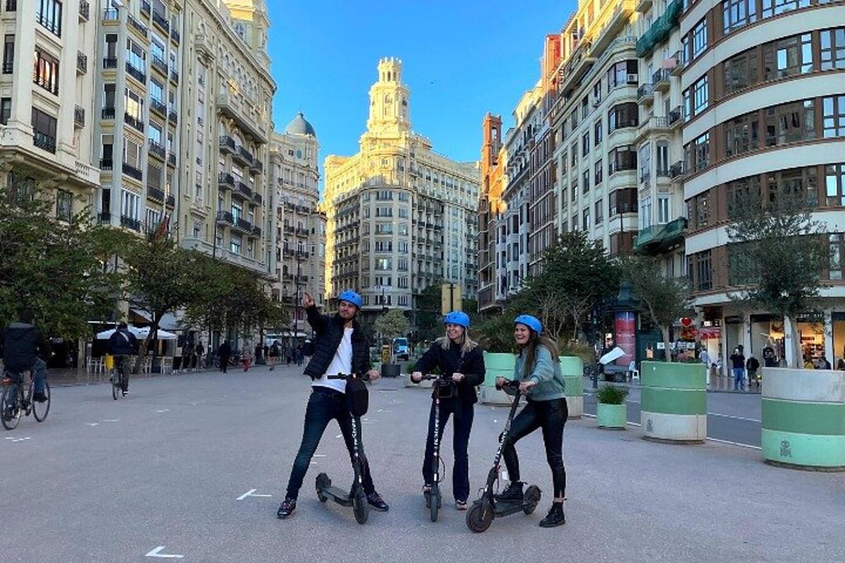 tre persone che scendono su skateboard lungo una strada cittadina