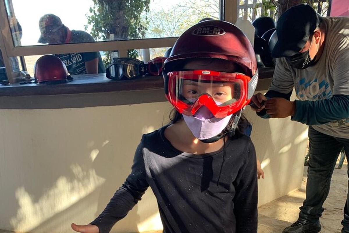 uma garotinha usando um capacete e uma máscara vermelha