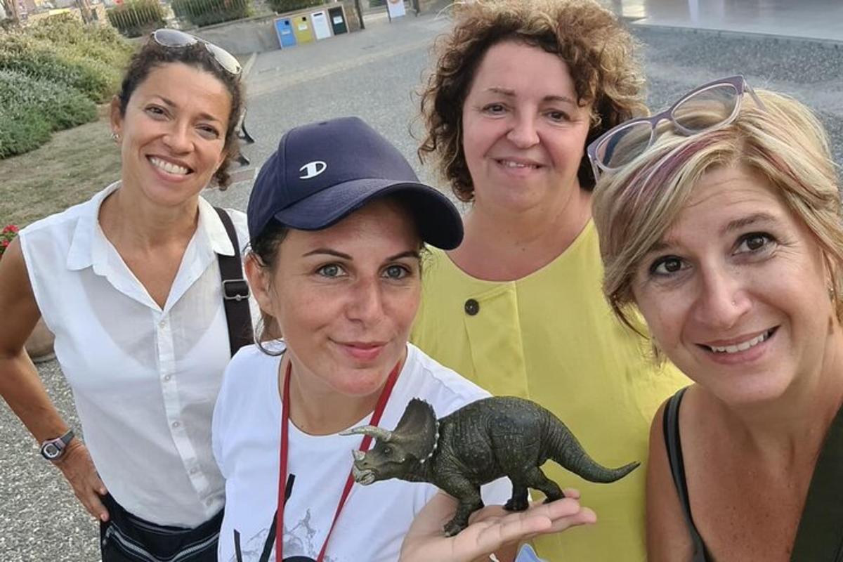 grupa žena pozira s igračkom dinosaurusom