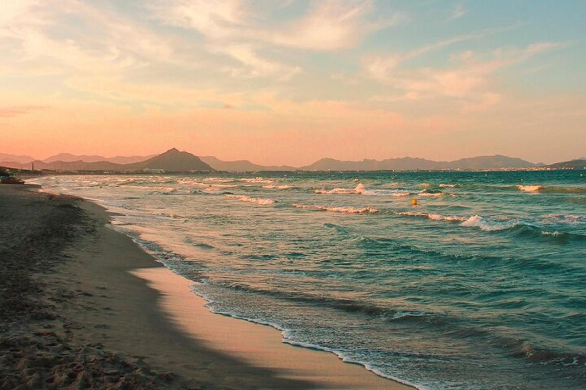 ein Strand mit Menschen im Meer bei Sonnenuntergang