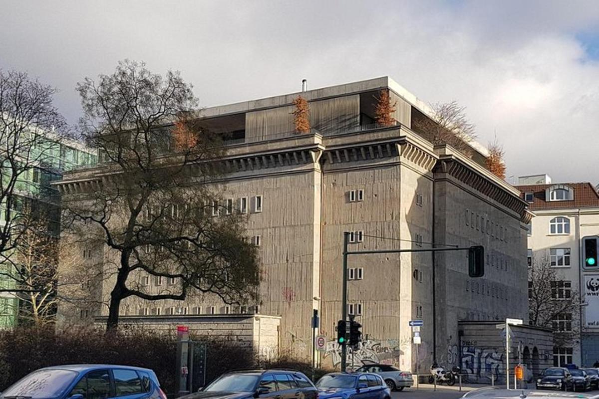 Un gran edificio con coches aparcados delante.