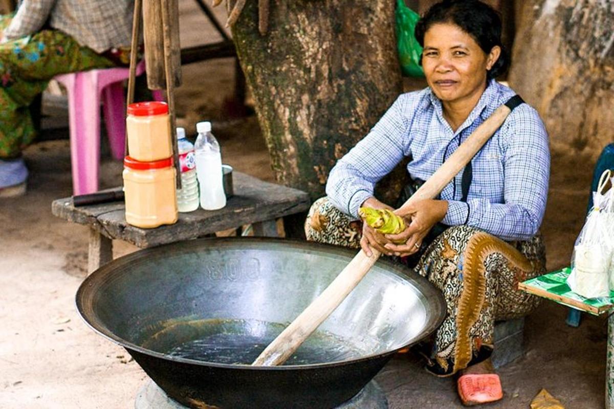 Una mujer sentada junto a un tazón grande con palillos.
