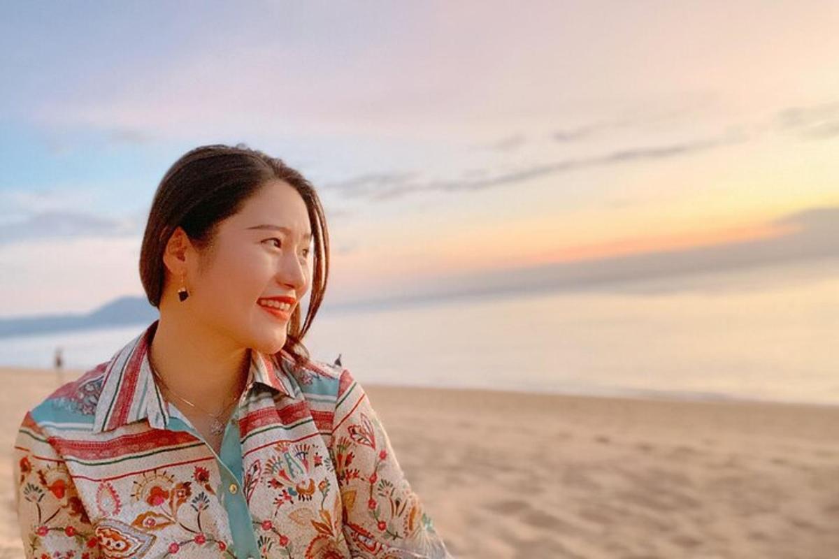 una mujer parada en la playa al atardecer