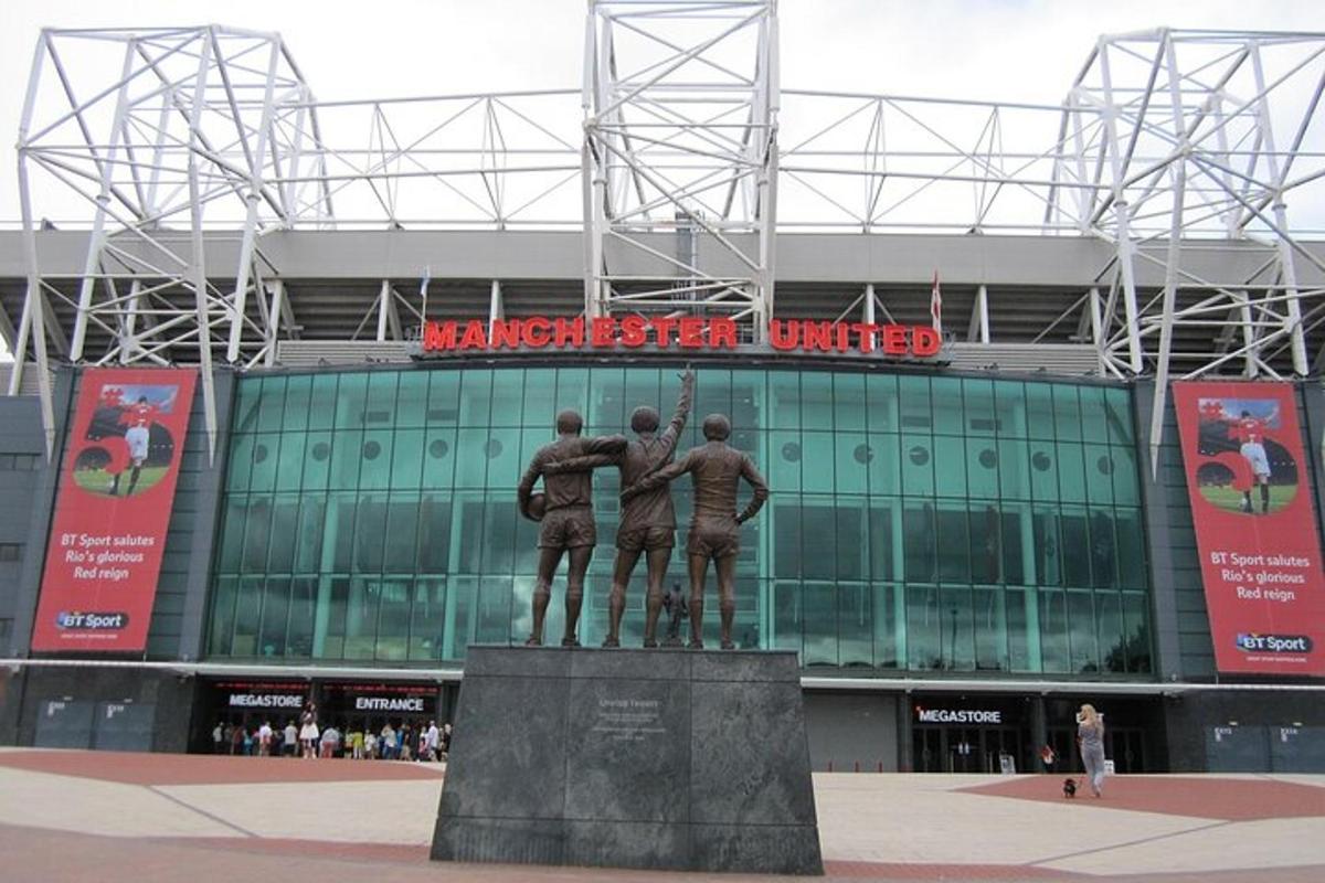 una statua di tre uomini davanti a uno stadio