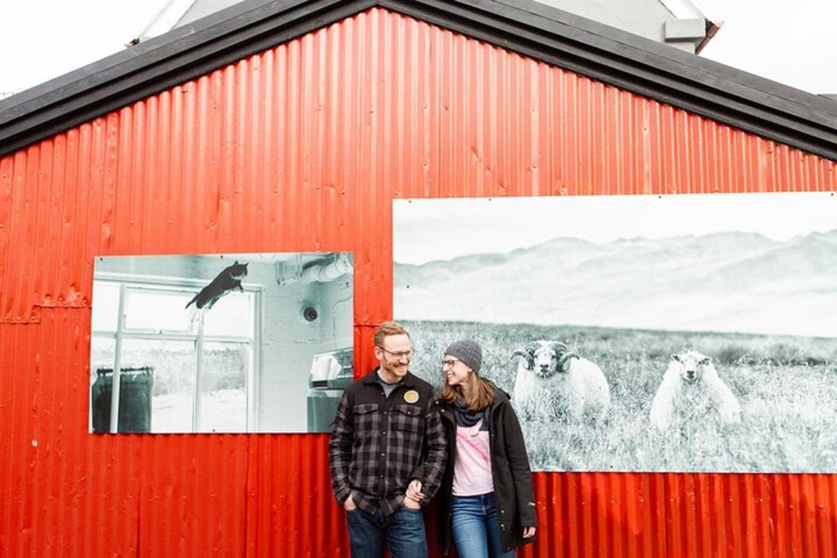 a man and a woman standing in front of a red barn