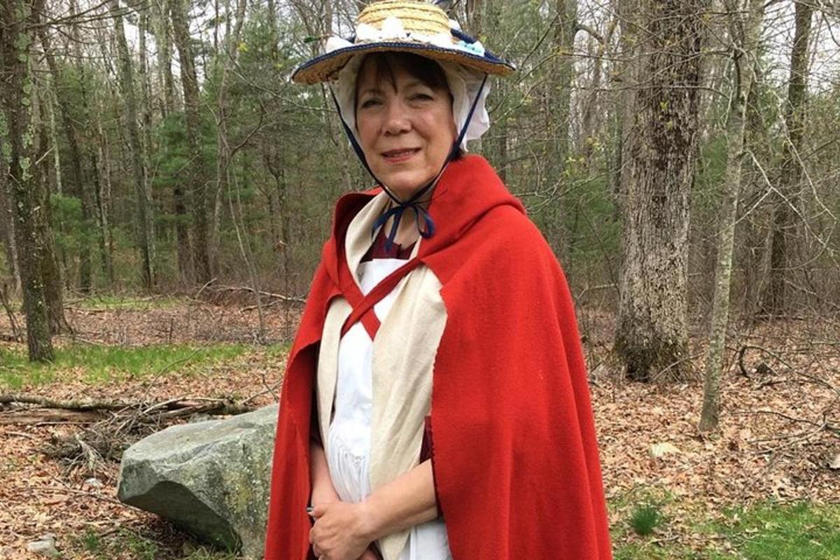 a woman dressed in a red cape standing in the woods