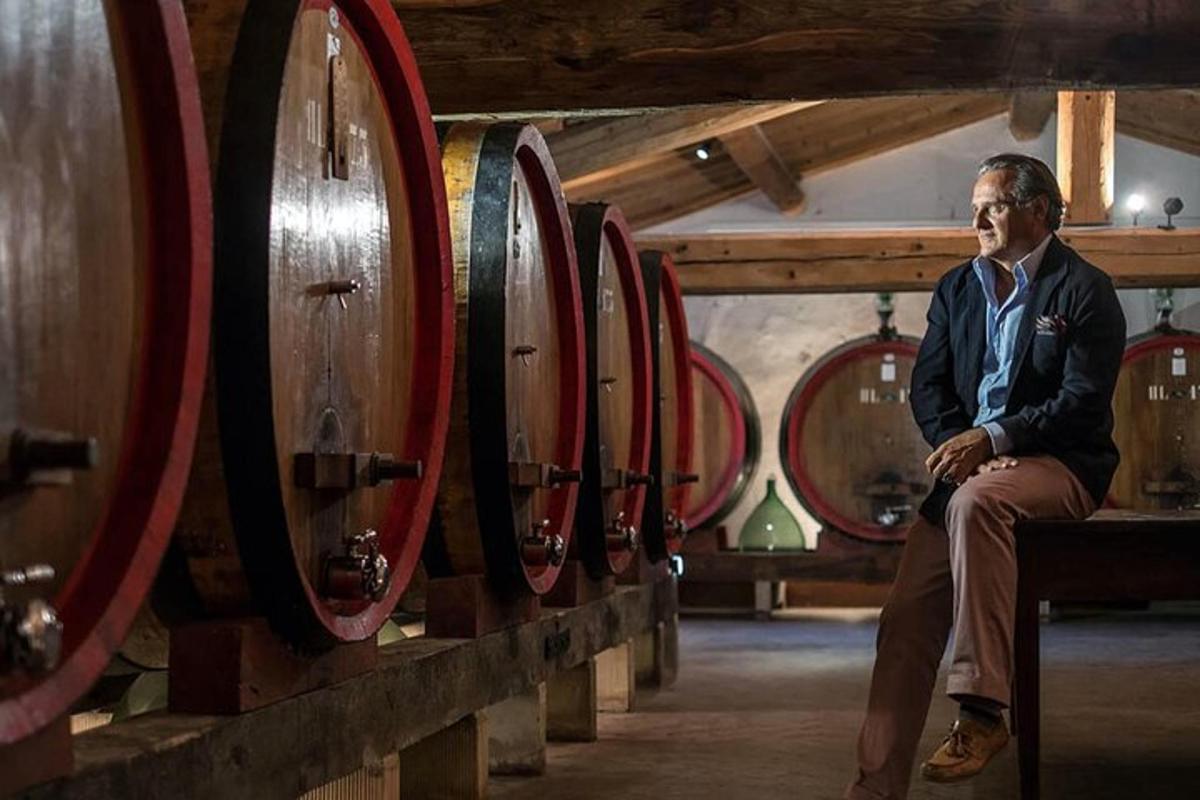 un uomo seduto su una panchina in una fila di botti di vino