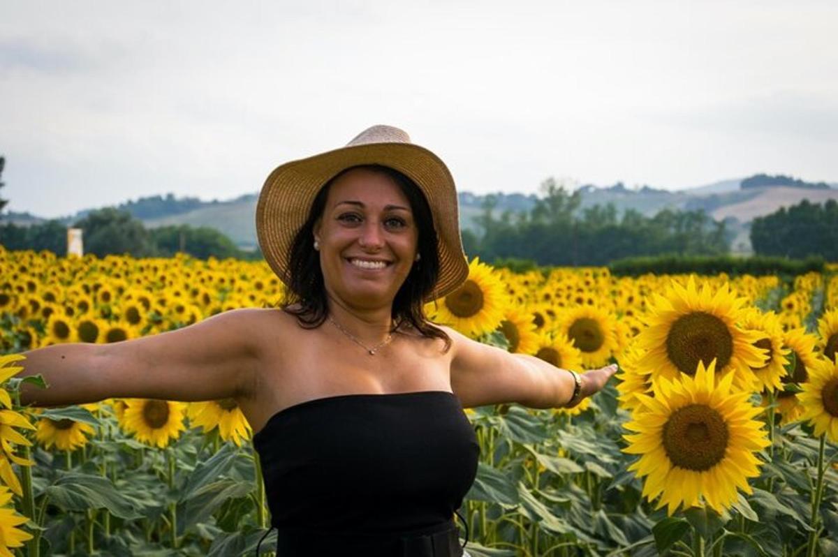 una donna con un cappello in piedi in un campo di girasoli