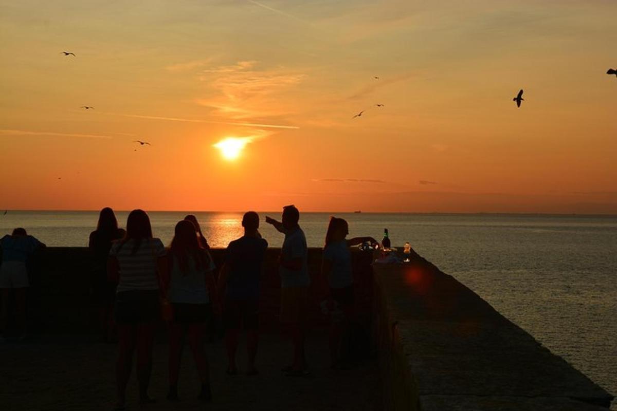 a group of people standing on a pier watching the sunset