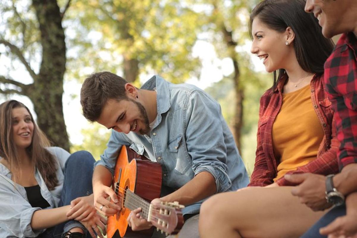 um grupo de pessoas sentadas ao redor de um homem tocando violão