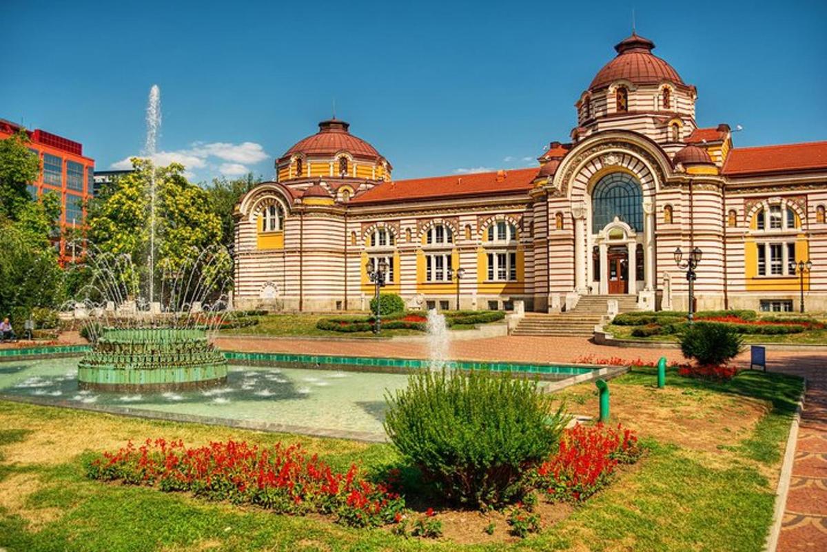 Un gran edificio con una fuente delante.