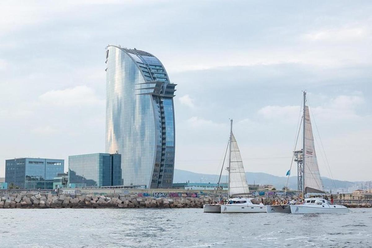 two sailboats in the water in front of a tall building