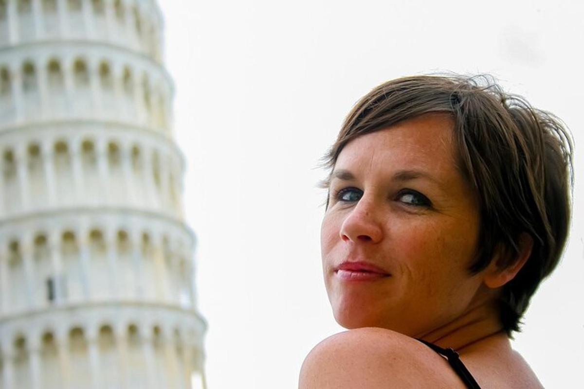 uma mulher está parada em frente à torre inclinada