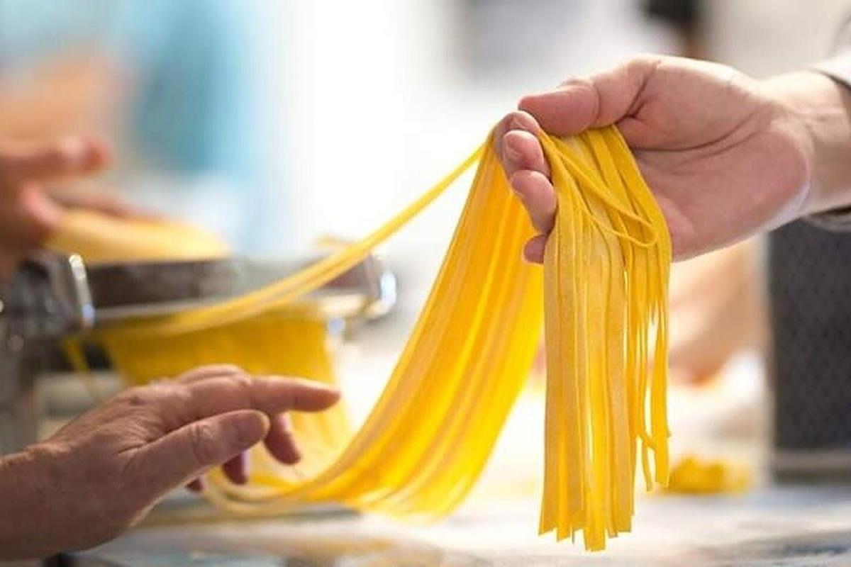 cilvēks tur uz galda spageti ķekaru