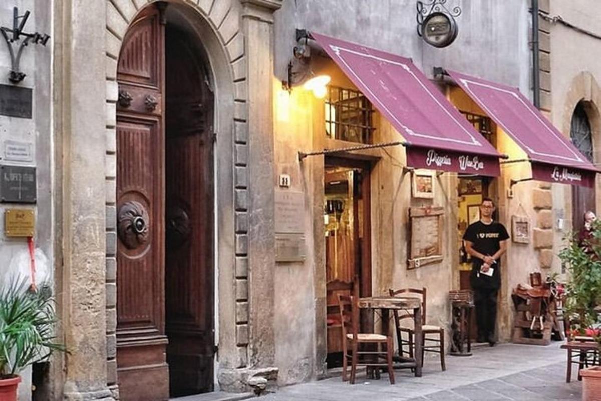 Ένας άντρας στέκεται έξω από ένα κτίριο με τραπέζια και καρέκλες