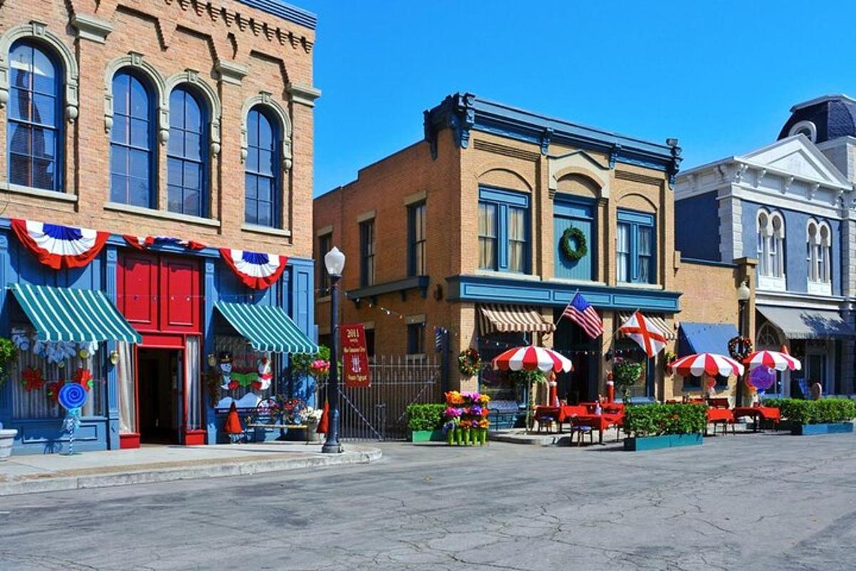 a city street with buildings and tables and umbrellas