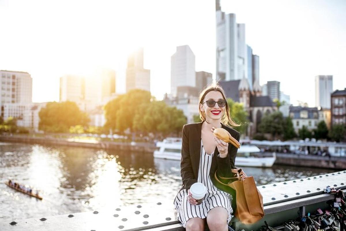 a woman sitting on a bridge eating a hot dog