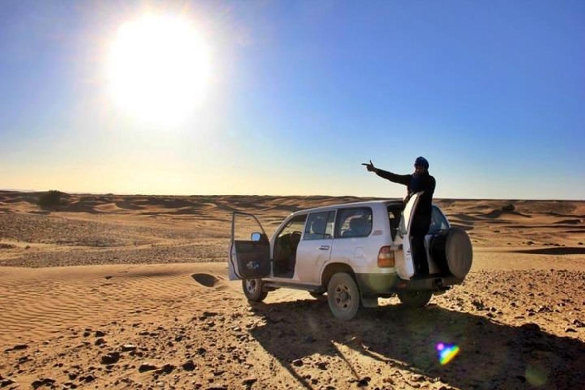 un uomo in piedi in cima a una jeep nel deserto