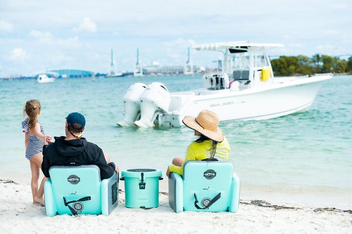 tiga orang duduk di pantai dengan perahu di air