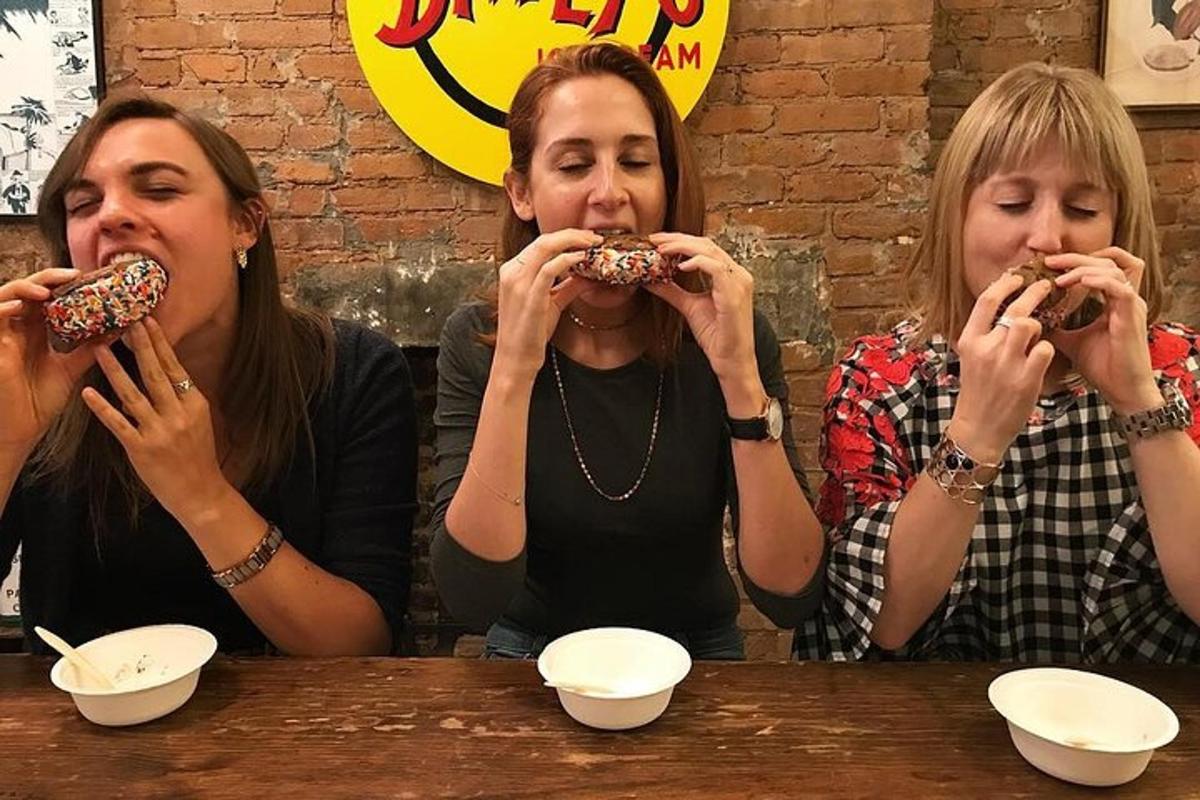 three women sitting at a table eating donuts