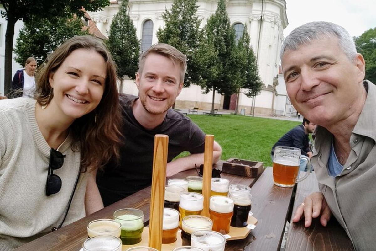skupina tří lidí sedících u stolu s pivem