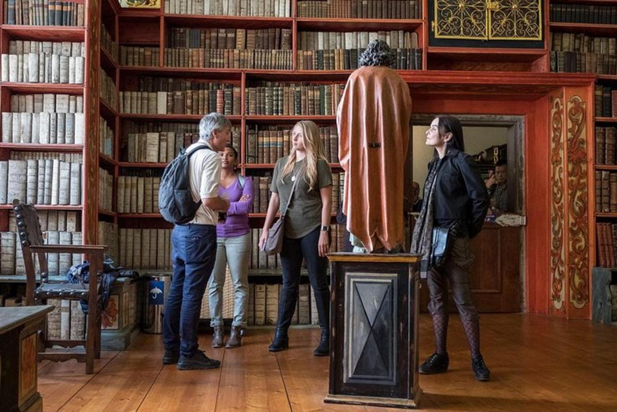 um grupo de pessoas em pé ao redor de uma estátua em uma biblioteca