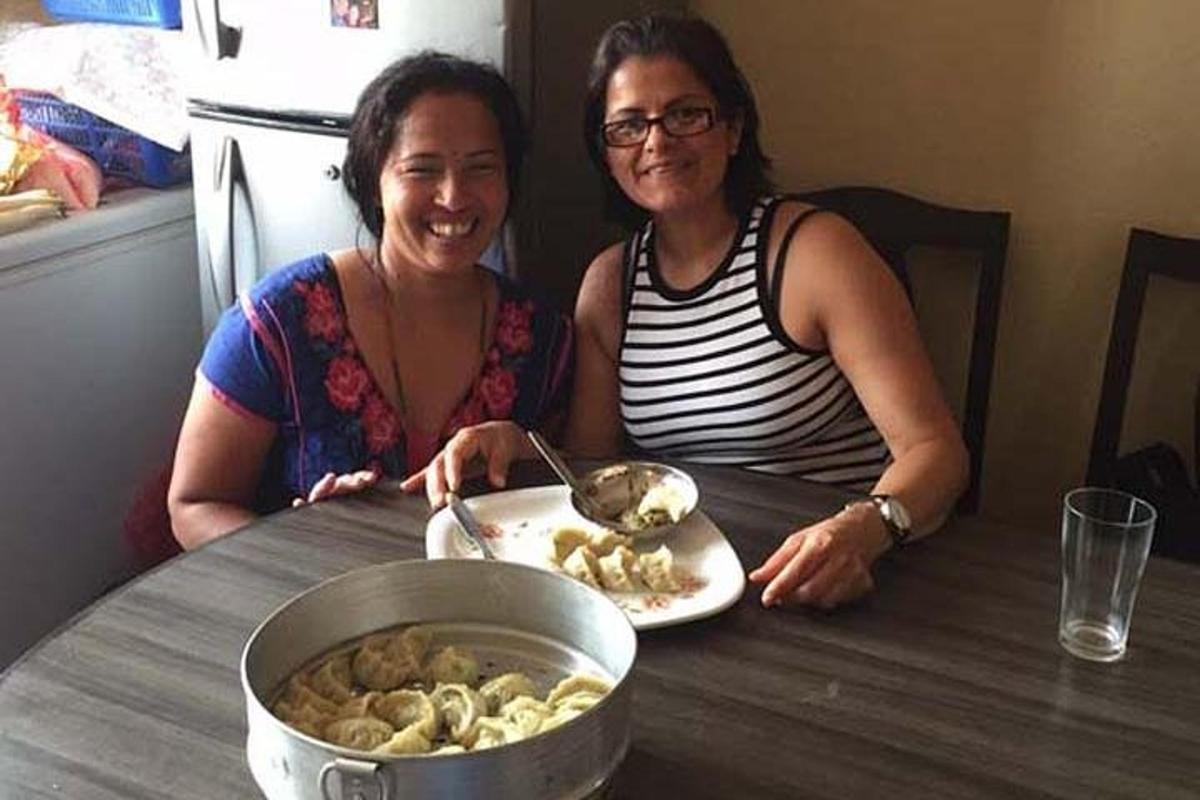 two women sitting at a table with a plate of food