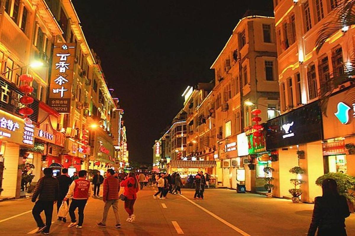 a group of people walking down a city street at night