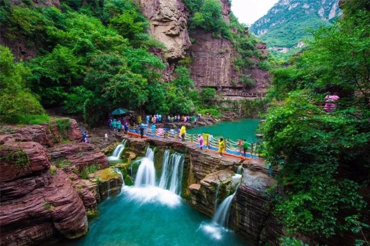 un gruppo di persone in piedi su un ponte sopra una cascata
