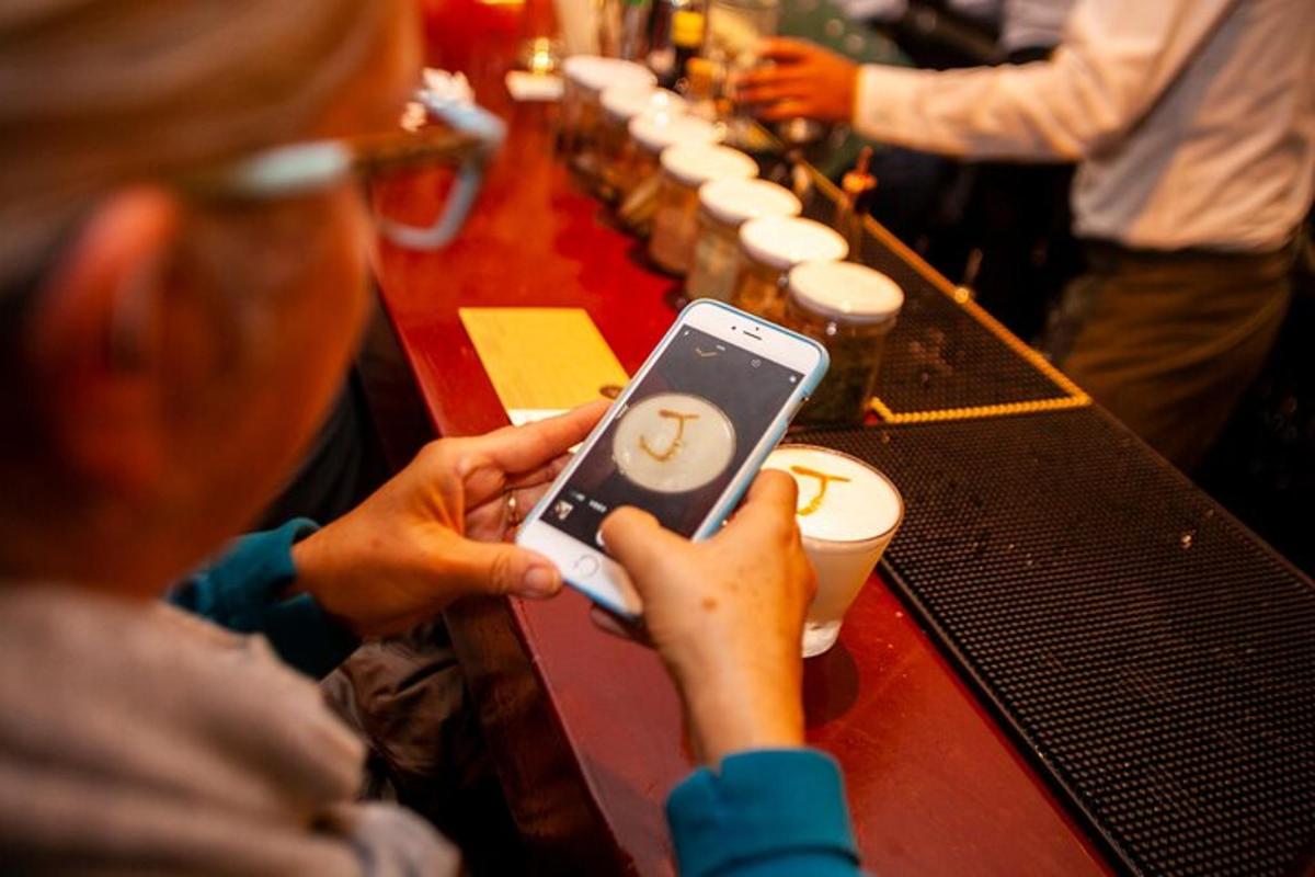 osoba držící mobilní telefon před barem