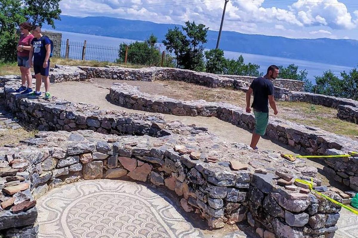 Dos hombres de pie frente a un muro de piedra