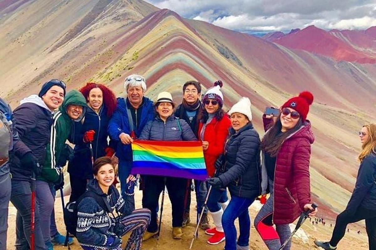 eine Gruppe von Menschen, die eine Regenbogenfahne vor einem Berg halten