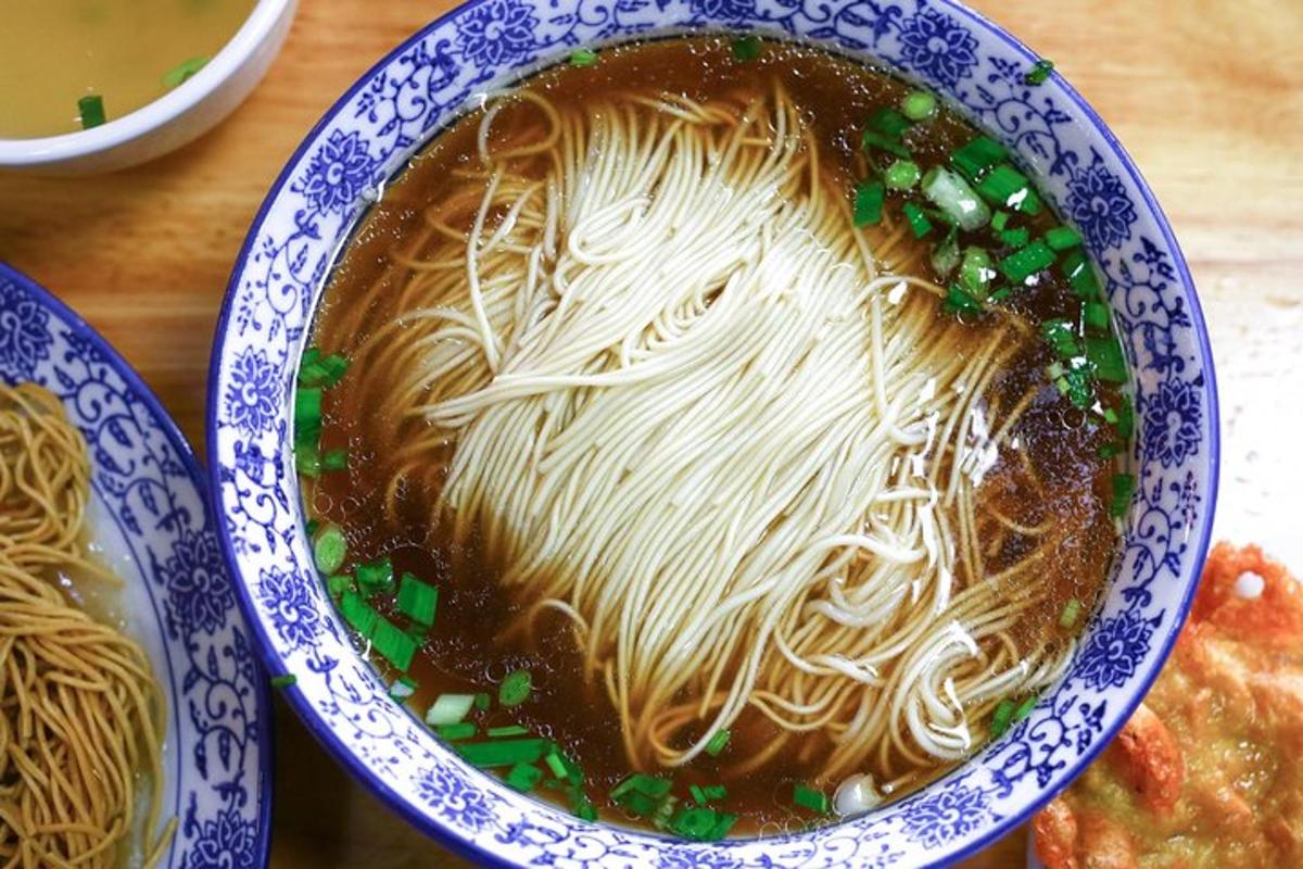 a bowl of noodle soup in a blue and white bowl