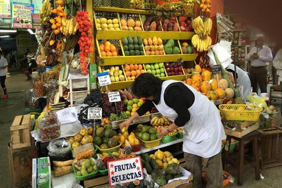 een man die bij een fruitkraam op een markt staat