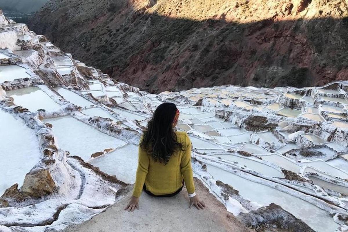 눈 덮인 산을 바라보며 바위에 앉아 있는 여자