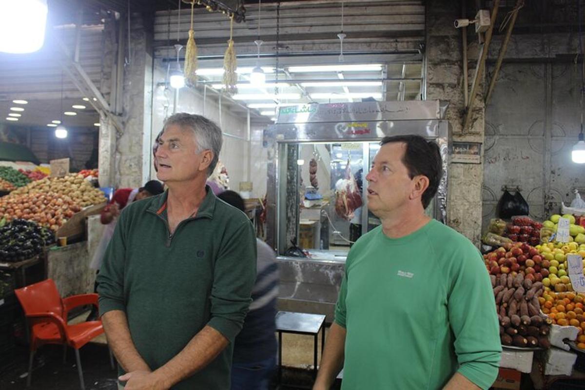 two men standing in front of a fruit market