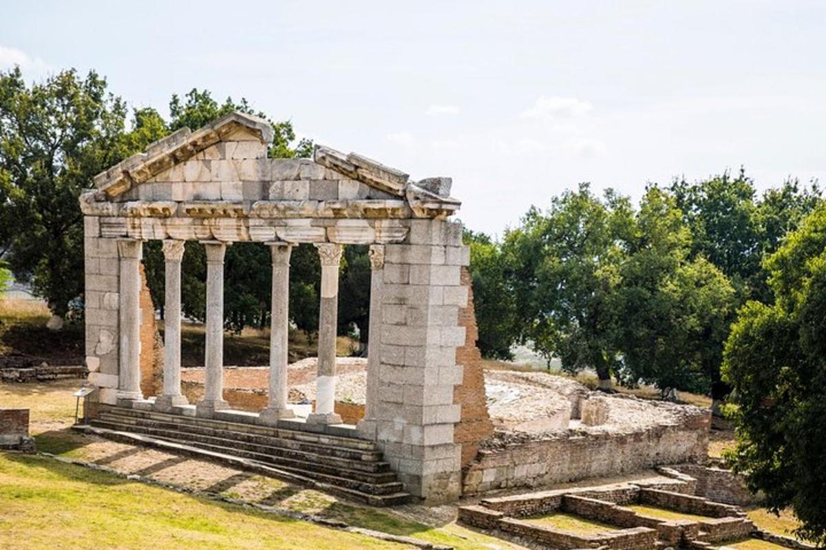 ένα μικρό πέτρινο κτίριο με κίονες σε ένα χωράφι