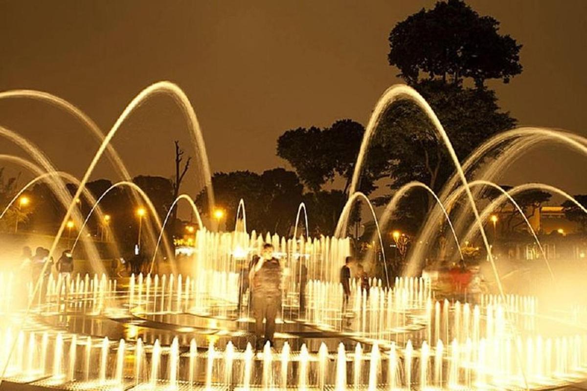 a group of water fountains in a park at night