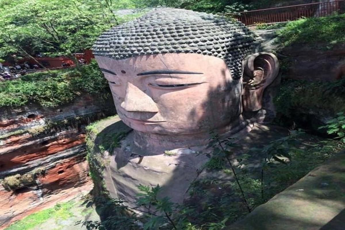 a statue of a large head in a garden