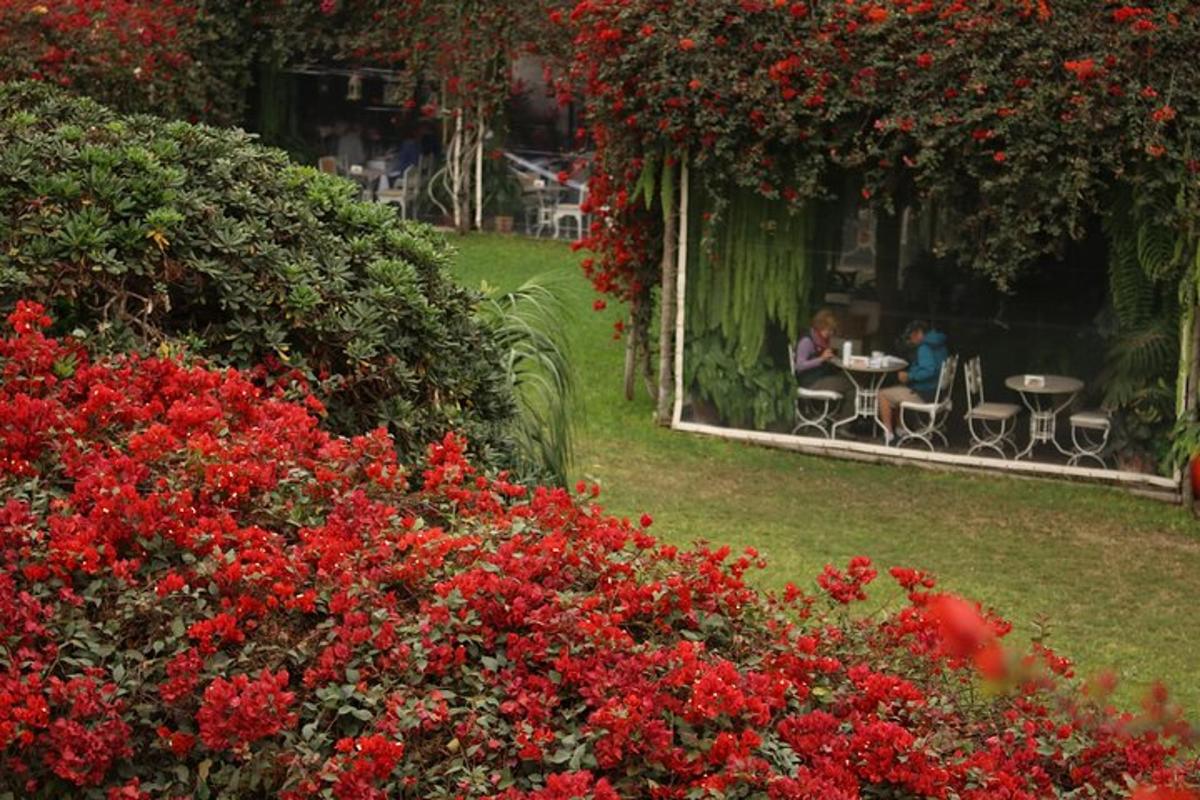 สวนที่มีดอกไม้สีแดงและผู้คนนั่งอยู่ที่โต๊ะ