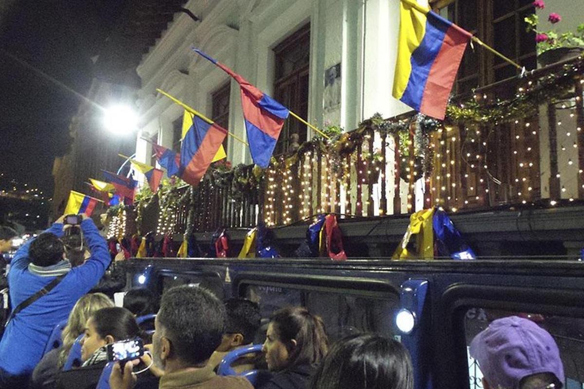 a crowd of people taking pictures of a bus with flags