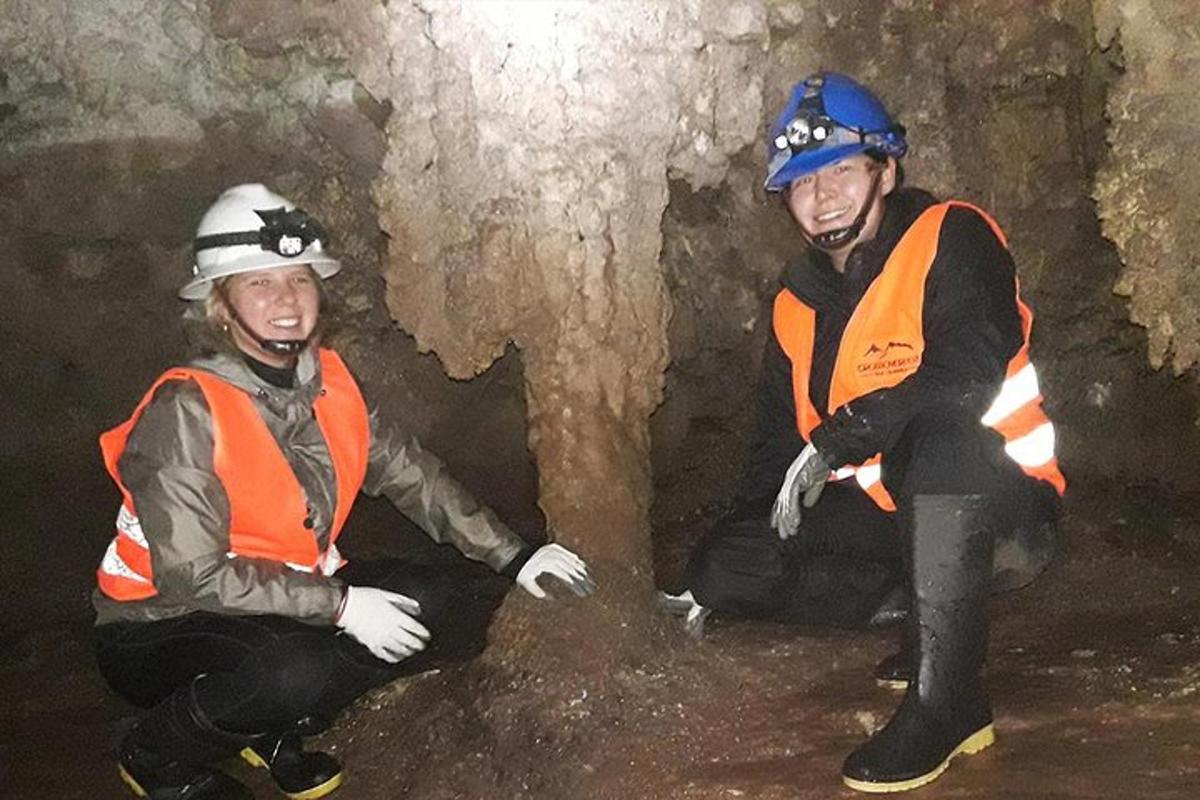 Dva muži sedí v jeskyni a mají na sobě bezpečnostní vybavení