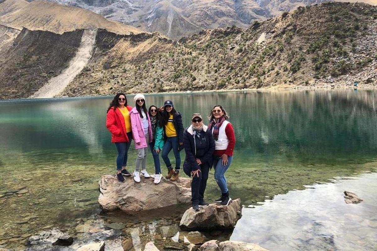 um grupo de pessoas em pé sobre rochas em frente a um lago