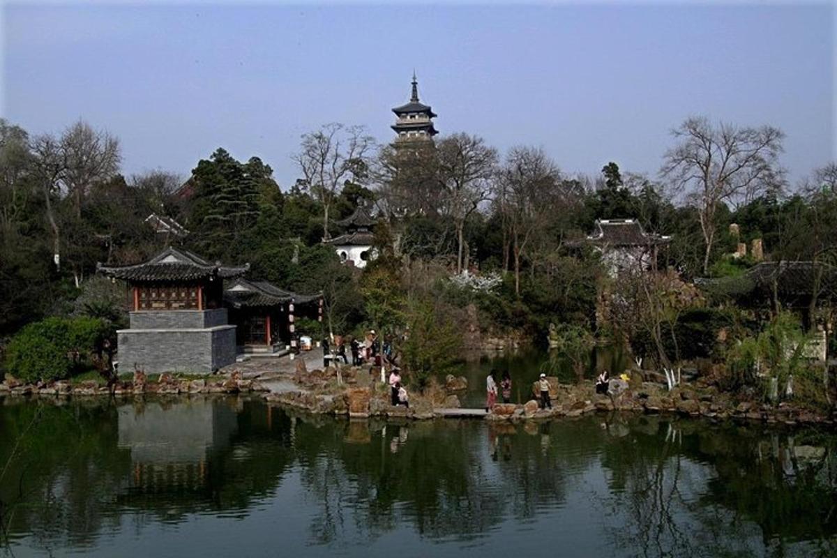a group of people walking around a pond in a park
