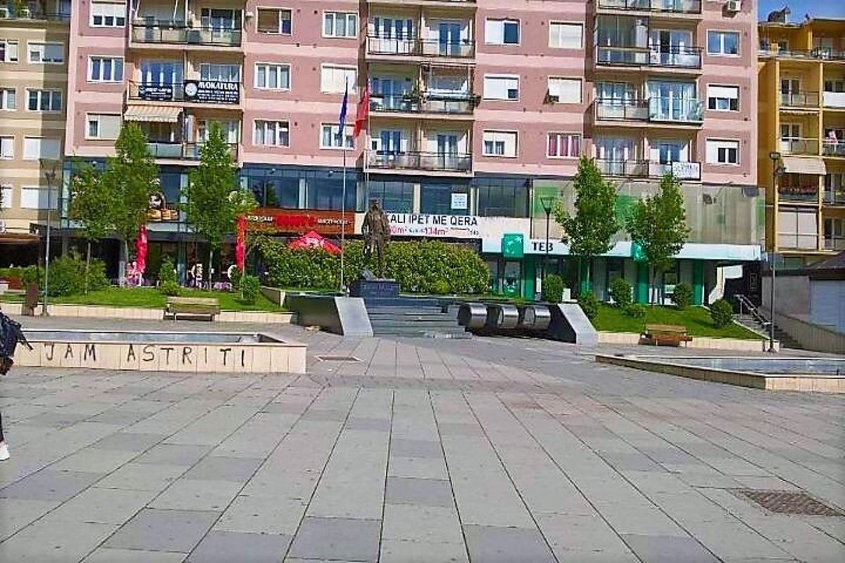 a person walking in front of a pink building
