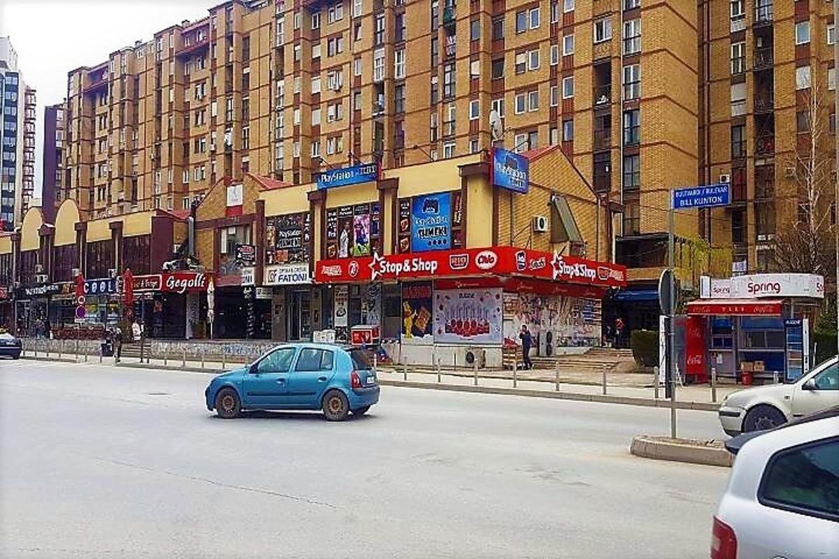 malé modré auto jedoucí po ulici s budovami
